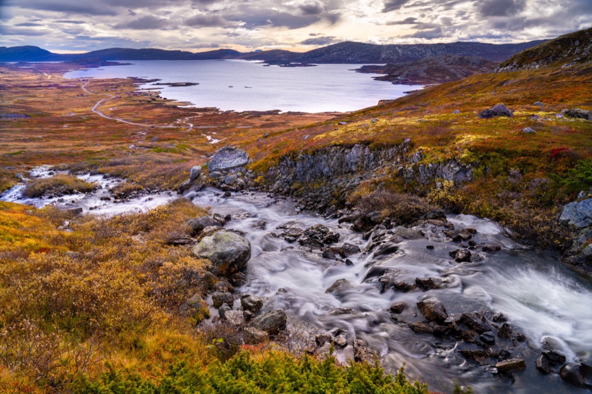 Górski potok spływający jesienną tundrą w stronę jeziora w Jotunheimen